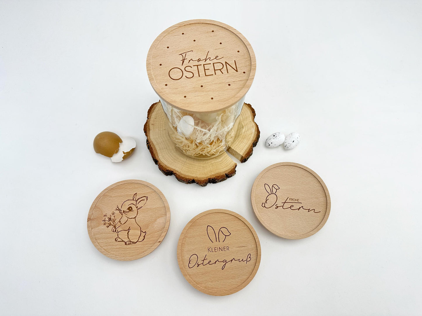 Personalisierte Vorratsgläser mit gravierten Holzdeckeln als Osterdeko. Die Deckel zeigen verschiedene Ostermotive wie einen süßen Hasen, 'Frohe Ostern' und 'Kleiner Ostergruß'. Ideal zum Befüllen mit Süßigkeiten, Ostereiern oder kleinen Geschenken. Perfekt als nachhaltige Osterverpackung oder stilvolle Frühlingsdekoration.