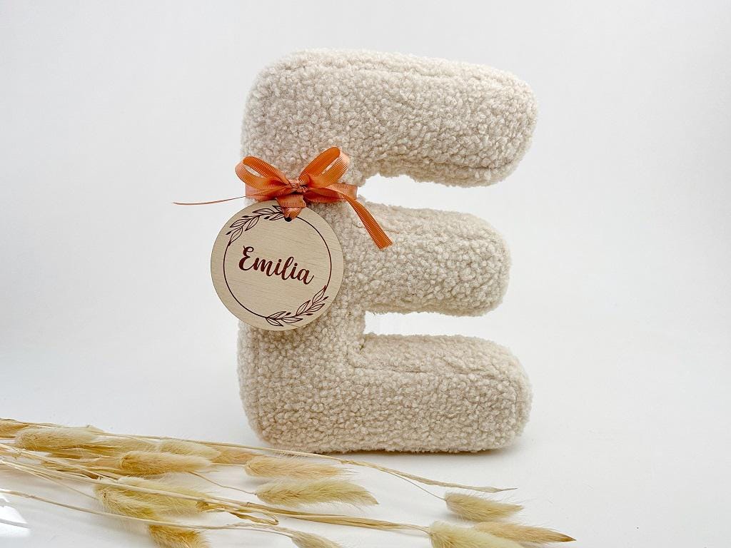Buchstabenkissen E in Wollweiß mit floralem Holzanhänger – Geschenk zur Geburt
