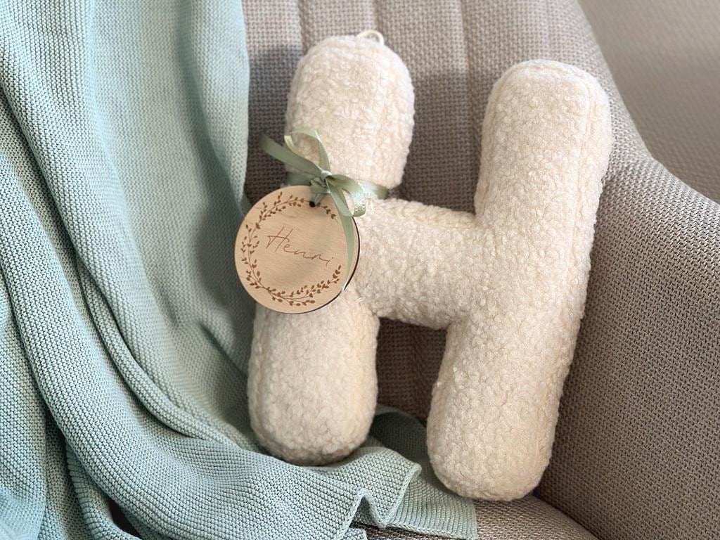Wollweißes Kissen H auf Kinderbett – Deko mit floraler Holzscheibe